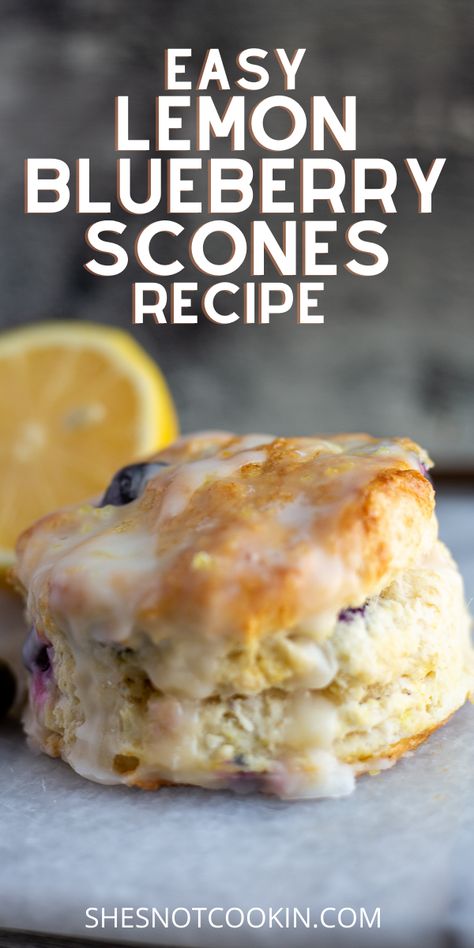 An image of a Lemon Blueberry Scone, drizzled with a light glaze resting on a grey marble board. A sliced lemon sits in the background as garnish. The purpose of this image is to show the completed recipe. Oreo Scones Recipe, Blueberry Scone Recipes, Blueberry Scones With Buttermilk, What To Bake With Buttermilk, Scones Made With Buttermilk, Lemon Brunch Recipes, Awrey Bakery Recipes, Blueberry Brunch Recipes, Blueberry Tea Biscuits