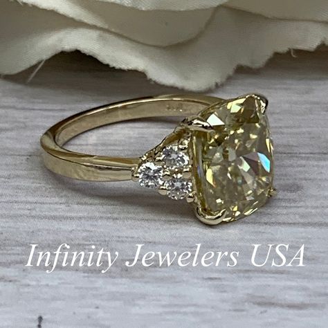 "This ring is an elongated cushion cut yellow Moissanite with round accents in 14k yellow gold #7007 One only We feature the finest quality of lab grown stones in the world. The properties of lab-grown are physically, chemically and visually identical to natural, just grown in a lab setting. White sapphire are more translucent than other stones. -Approximate total carat weight: 5.30ctw diamond equivalent -Center Stone Size: approx. 5.00ct. diamond equivalent -Center Stone Shape: elongated cushio Colored Diamond Engagement Rings, Engagement Ring Yellow, Elongated Cushion Cut, Elongated Cushion, Cushion Engagement Ring, Yellow Engagement Rings, Gold Diamond Engagement Rings, Glass Designs, Gold Gift