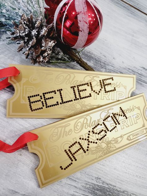 "We are so excited to share these new personalized ornaments with you! Polar express ornament personalized train ticket Christmas ornament polar express train ticket gold believe magic acrylic ornament We engrave gold acrylic ornament with your choice  and punch out the personalized name or word of your choosing they are then hung red ribbon to easily add to your tree or Christmas stocking. Choose from either \"BELIEVE\" or your Childs name to be cut out as if it were hole punched! Tags ornaments are 6inches x 2.5 inches to provide a perfect size ornament or stocking tag.  These ornaments are sure to add to your Christmas magic this year and for years to come. please note the back of these are black due to the fact they are made from mirror acrylic" The Polar Express Christmas Decorations, Diy Train Ornaments, Diy Polar Express Ticket, Polar Express Themed Christmas Tree, Polar Express Theme Christmas Tree, Polar Express Tree Ideas, Polar Express Decorations Diy, Polar Express Christmas Decor, Polar Express Christmas Tree Theme