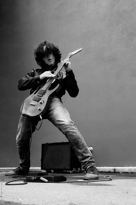 Black and white portrait of stylish rock musician playing electric guitar in the street against of wall Rockstar Playing Guitar, Rock Black And White, Guitarist Portrait, Guitar Playing Poses, Person Playing Electric Guitar Reference, Poses With Electric Guitar, Man Playing Electric Guitar, Rock Portrait, Guitar Poses For Men