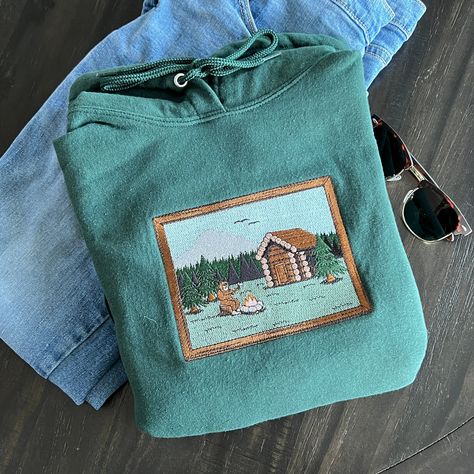 Introducing the first of our embroidered Scenic Collection, "Sasquatch Cabin"! This high detail artwork was designed and embroidered from scratch by us. Our hoodies and sweatshirts are made from high-quality fabric and feature unique embroidered designs. Whether you're looking for a stylish garment for yourself or a unique gift for a loved one, our embroidered clothing is guaranteed to satisfy! Don't forget to select a color that specifies 'Crewneck' or 'Hoodie' to choose your garment type. Hood Vintage Long Sleeve Hoodie For Outdoor, Mountain Embroidery Hoodie, Cozy Crew Neck Hoodie For Outdoors, Cozy Outdoor Hoodie Sweatshirt, Mountain Clothes, Outdoor Graphic Print Crew Neck Sweatshirt, Camping Gift Ideas, Camping Forest, Granola Outfits