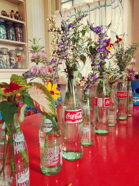 Vintage Soda Bottles Decor, Soda Bottle Centerpieces, Flowers In Coke Bottles, Coke Bottle Centerpiece, Glass Bottle Flower Vase, Soda Bottle Flowers, Coke Bottle Flowers, Vintage Grad Party, Glass Soda Bottle Crafts