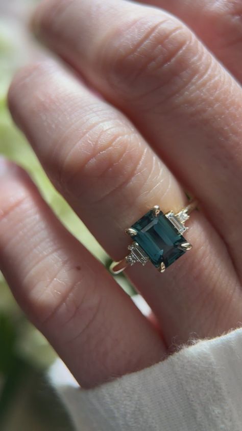 This captivating 14K yellow gold ring features a stunning 2.65 carat emerald-cut natural sapphire (heated).  Its vibrant hue and impressive size are beautifully complemented by a halo of sparkling 0.15 carat VS, F-G diamonds, adding extra brilliance.  The ring's slender 1.7mm band provides a classic silhouette, perfect for everyday wear. A gemological report can be purchased separately for added assurance. Engagement Rings Teal Sapphire, Emerald Cut Engagement Ring With Emeralds, Emerald Cut Engagement Ring Sapphire, Emerald Cut Gemstone Ring, Art Deco Ring Sapphire, Emerald Cut Emerald Ring, Emerald Engagement Rings, Emerald Cut Sapphire Ring, Teal Sapphire Ring