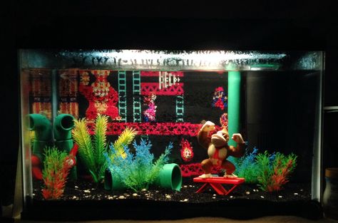 Donkey Kong arcade fish tank. Features hand painted PVC pipe and plant decor. The Donkey Kong figurine was purchase at a toy store. One of the pipe features a bubbler system that can be controlled with the red valve. Themed Fish Tank, Arcade Theme, Beta Tank, Unique Fish Tanks, Animal Enclosures, Fish Tank Themes, Glass Fire Pit, Aquarium Ideas, Nature Aquarium