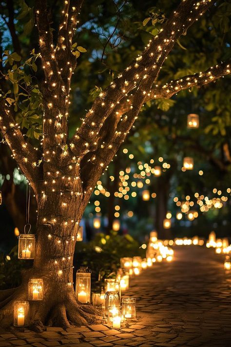 Enchanted forest theme wedding outdoor decor with a tree decorated with fairy lights and tiny lanterns under the tree there is a paved ground lined. Let your big day become a magical woodland affair with these enchanting forest wedding ideas that’ll make your guests feel like they’ve stepped into a fairy tale. Enchanted Forest Ceremony, Enchanted Forest Wedding Entrance, Tree Lights Wedding, Enchanted Forest Prom Theme, Tree Lights Wedding Enchanted Forest, Enchanted Forest Aesthetic Light, Magical Wedding Theme Night Lights, Enchanted Forest Night Time Photo Backdrop, Victoria Woodhull