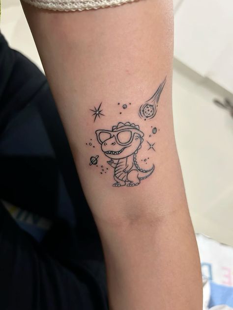 Funny Space Tattoo, Dinosaur Simple Tattoo, Dinosaur On A Skateboard Tattoo, Mother Son Dinosaur Tattoo, Dinosaur Line Tattoo, Cute Dino Tattoo Ideas, Funny Dinosaur Tattoo, Space Dinosaur Tattoo, Space Dragon Tattoo