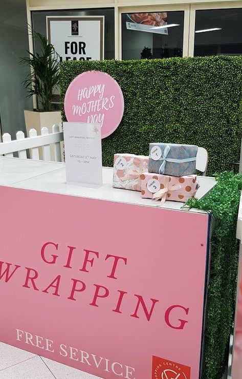 Desk with giftwrapping front banner, with a hedge wall behind. Gifts wrapped sit on the desk. Gift Wrapping Station, Wrapping Station, Sale Promotion, Retail Display, Christmas Sale, Happy Mothers, Mother Gifts, Mothers Day, Promotion