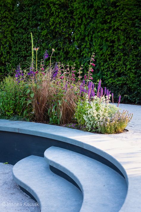 Limestone steps wrap around a sunken seating area to form a bench with a colourful planting bed behind. Curved Steps, Limestone Steps, Sunken Seating Area, Pixie With Bangs, Sunken Seating, Tom Simpson, Residential Garden, Flower Event, Curved Patio