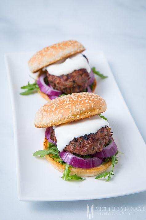 Two minted lamb burgers on a white plate Minted Lamb Burgers, Lamb Burger Recipe, Tailgate Food Ideas, Spicy Sausage Dip, Sausage Dip Recipe, Easy Lamb Recipes, Muhammara Recipe, Lamb Burger Recipes, Lamb Burger