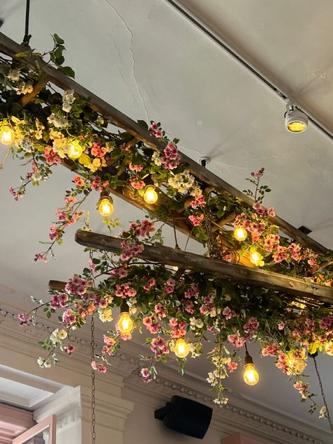 Floral Decor Restaurant, Ceiling Hanging Floral Decor, Hanging Faux Flowers From Ceiling, Ceiling Plant Decor, Flower Shop Lighting, Faux Flower Ceiling, Neutral Massage Room, Moody Floral Decor, Floral Restaurant Design