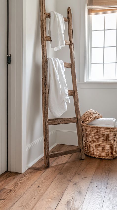 Light-filled bathroom with white walls, wood floors, a wooden ladder, and a basket of towels, showcasing warm, natural tones. Ladder Behind Toilet, Wooden Towel Ladder Bathroom, Guest Bathroom Hand Towel Ideas, Bathroom Hand Towel Ideas, Towel Ladder Bathroom, Warm Wood Floors, Half Bathroom Decor Ideas, Behind Toilet, Bathroom Ladder