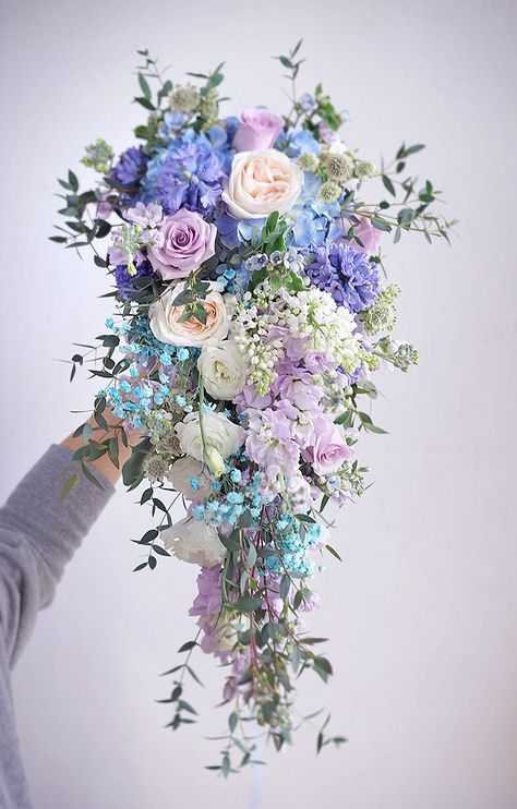 Blue And Purple Cascading Bouquet, Pastel Cascade Bridal Bouquet, Pastel Blue And Lavender Wedding, Light Blue And Purple Bouquet, May Wedding Bouquet Brides, Pink Purple Blue Bridal Bouquet, Periwinkle Flower Bouquet, Blue And Purple Bridal Bouquet, Mermaid Flower Arrangement