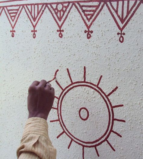 Artist painting a freehand circular motif Bheenth Chitra, Warli Designs, Terrace Wall, Pots Painting, Mud Art, Worli Painting, Tulsi Plant, Warli Painting, Wall Drawings