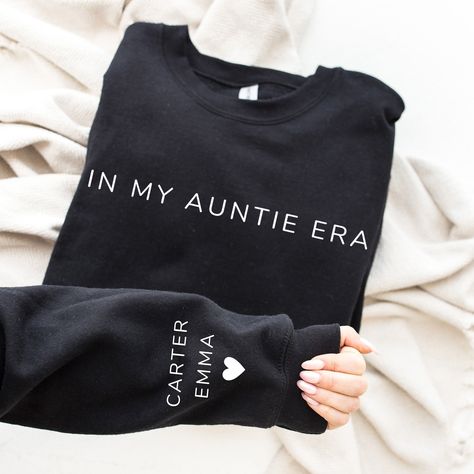 In My Auntie Era With Kid Name On Sleeve Sweatshirt / Hoodie, Aunt Shirt, Gift For Mommy, Mother's Day, Mom Life, Custom Child Name Crewneck   🌿WELCOME TO UNIQUE TRENDS DESIGN  If you are looking for soft, comfy, first-rate sweatshirts, you're in the right place! Here at Unique Trends Design, we love what we do and strive to make your shopping experience just right for you. If you have any questions, concerns, or comments about our products, feel free to shoot us a message anytime. Even on weekends and holidays, we'll try our best to respond as quickly as possible! Product Details Unisex Sweatshirts: - Gildan Brand -50% cotton - Light/medium weight and soft, this sweatshirt is sure to be your next favorite sweatshirt. 🌿Sizing and Coloring Please make sure you select the right color and s Cricut Sweaters, Aunt And Niece Shirts, Auntie Era, In My Mom Era, Mama Crewneck, Auntie Shirts, Aunt Shirts, Auntie Gifts, Mom Era