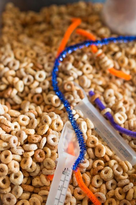 A simple cereal sensory bin for toddlers with threading activity Cheerio Sensory Bin, Sensory Rice Activities, Cereal Sensory Play, Cheerio Sensory Play, Rice And Beans Sensory Bin, Reasoning Activities, Sensory Tubs, Nutrition Activities, Infant Classroom