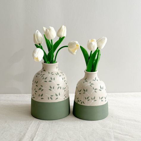 Enhance your home decor with our unique handmade ceramic vases. These elegant bottle-shaped vases feature beautiful green hues and intricate leaf engravings, making them both a perfect gift option and ideal for displaying dried flowers. Available as a 2-piece set (large and small) or individually, each vase is meticulously crafted to stand out as a unique piece.  DIMENSIONS: Large: ↕ Height: 18-19 cm. / 7.08 - 7.48 in.  Ø Diameter: 4 cm. / 1.57 in.  Small: ↕ Height: 15-16 cm. / 5.90 - 6.29 in. Ø Elegant Vases Decor, Easy Vase Painting Designs, Ceramic Vase Inspiration, Pottery Painted Vase, Cute Pottery Vase, Ceramic Painted Vase, Hand Painted Flower Vase, Ceramic Handmade Vase, Ceramics Flower Vase