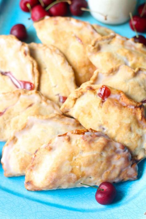 closeup of hand pies on a blue plate with cherries scattered around Cherry Hand Pies Recipes, Fruit Hand Pies, Cherry Hand Pies, Hand Pie Recipes, Fried Pies, Hand Pie, Cherry Recipes, Fresh Cherries, Hand Pies