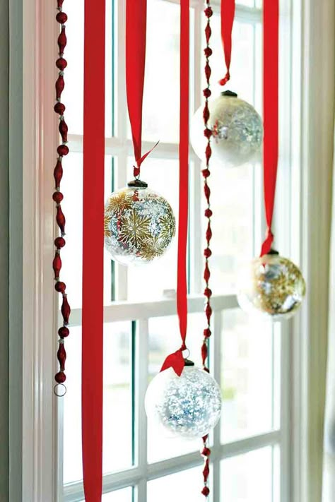 Silver and gold glass ball ornaments hung from red ribbon in a window Apartment Christmas, Christmas Apartment, Christmas Window Decorations, Christmas Decoration Ideas, Christmas Window, Christmas Decorating Ideas, Christmas Tree Ideas, Xmas Decor, Christmas Activities