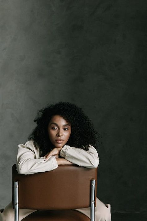 A Woman Sitting on a Chair · Free Stock Photo Woman With Afro, Minimalist Studio, Deep In Thought, Chair Pose, Studio Portrait Photography, Chic Dress Classy, Photographie Portrait Inspiration, Portrait Of A Woman, Sitting Poses