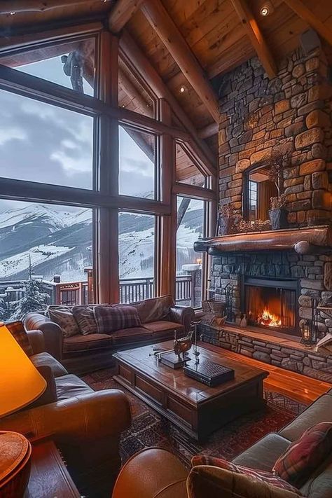 Rustic cabin living room with a stone fireplace, large windows showcasing a snowy mountain view, and warm wooden interiors. Alaskan House Interior, Winter Cabin Living Room, Cabin Interior Design Living Room, Artistic Fireplace, Mountain Home Interiors Cozy Cabin, Cozy Winter Cabin Interior, Room With Mountain View, Luxury Mountain Homes Interiors, Cabin Interiors Living Room