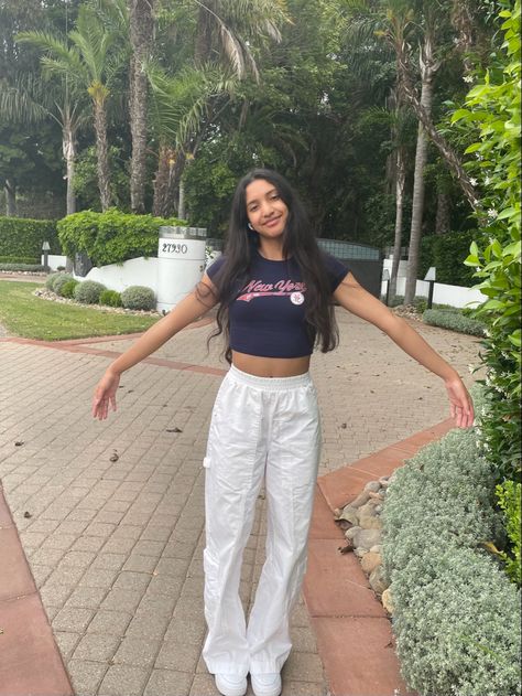 Aesthetic, Malibu mansion, green plants, lushes scenery, outfit inspo, clean outfit, white cargo pants, New York baby tee, blue tee shirt, white Air Force 1s, smiles, hair inspo, messy beach waves, beach vibes, aesthetic beach outfit, pic inspo, photo inspo How To Style White Cargo Pants, White Cargo Pants Outfit, Europe Fits, Baby Tea, White Cargo Pants, Beach Fit, Beach Fits, Cargo Pants Outfit, Pants White