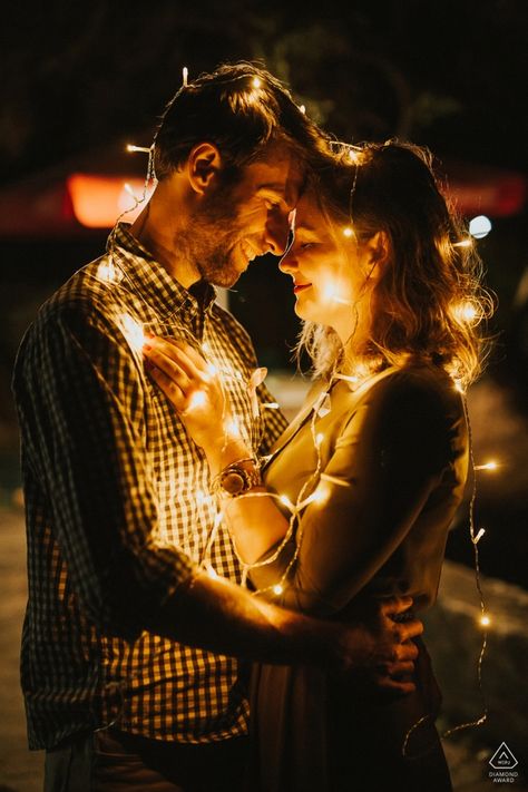 A Topoľčany, Slovakia couple drapes themselves in strands of lights while embracing for their engagement photoshoot with wedding photographer Martin Almasi Photoshoot With Christmas Lights, Night Photography Couple, Photoshoot Ideas Lights, Christmas Lights Photoshoot Couple, Couples Christmas Lights Pictures, Night Couple Photography, Couples Photoshoot Night, Night Time Engagement Photos, Christmas Lights Photoshoot