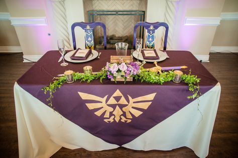 Our sweetheart table was rad. A large hand-painted purple cloth over it, Mr and Mrs goblets for our drinks, hand-painted chairs for us with the same design as our banners over the ceremony, complete with Zelda's sword from Twilight Princess.  https://www.etsy.com/listing/182141561/etched-legend-of-zelda-inspired  http://www.replicadungeon.com/princess-zelda-sword.html Legend Of Zelda Themed Wedding, Zelda Wedding Theme, Nintendo Wedding, Loz Wedding, Legend Of Zelda Wedding, Video Game Wedding, Zelda Party, Zelda Wedding, Purple Cloth