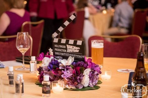 Movie clacker surrounded by purple floral as a reception table centerpiece for a movie wedding theme Theatre Wedding Ideas, Movie Wedding Theme, Cinema Themed Wedding, Movie Themed Wedding, Cinema Ideas, Loews Royal Pacific Resort, Movie Wedding, Ballroom Reception, Cinema Wedding