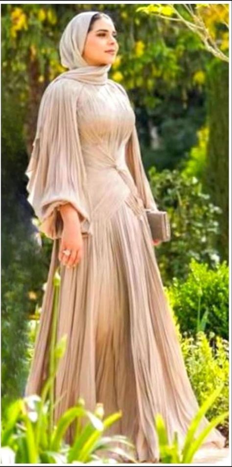 Woman in a hijab wearing a gold pleated dress with big sleeves, full skirt and a tie in the front Wide Dresses Hijab, Hijabi Evening Gowns, Gold Dress Hijab, Hijabi Prom Dress Classy, Soiree Dresses For Hijab, Hijab Business, Gold Dress Outfits, Muslim Prom Dress, Prom Dresses Classy