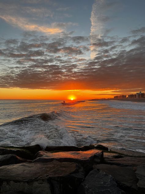 a orange sunrise at the beach, there’s man surfing really far. Before the water, there’s some black rocks Nyc Summer, Fall Mood Board, Rockaway Beach, Fall Mood, Sunrise Beach, Dream Lifestyle, Summer Sun, Boyfriend Pictures