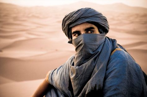 This image is of a man from somewhere in Africa. He is wearing what is known as a tagelmust. This garment is a very long veil or turban; about 16.5 ft long. It is beaten until it shimmers and is dyed indigo. These people live near the Sahara and this veil helps to shield them from heat and duststorms. They are called "blue people" because the indigo dye rubs off on their skin. Renee Ahdieh, Tuareg People, Disney Aladdin, We Are The World, Arabian Nights, Libya, People Of The World, In The Desert, North Africa