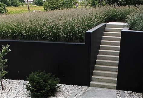 painted retaining wall Charcoal Garden Wall, Black Concrete Retaining Wall, Contemporary Retaining Wall Ideas, Painting Retaining Walls, Painted Concrete Retaining Wall, Retaining Wall Cover Up Ideas, Black Retaining Wall Garden, Painted Retaining Wall Ideas, Black Cinder Block Wall