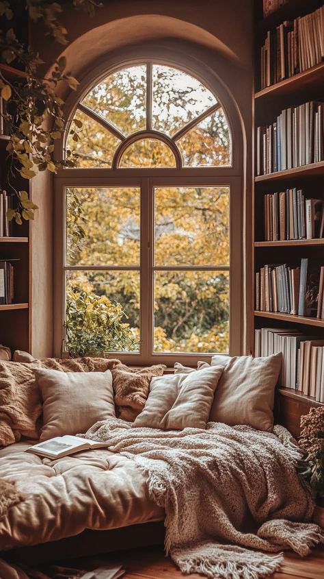 Cozy reading nook with plush cushions, blankets, arched window, and bookshelves in warm tones for serene contemplation. Books Aesthetic Bedroom, Bookish Bedroom Aesthetic, Bedroom With Library, Book Bedroom Ideas, Bookish Bedroom, At Home Library, Window Framing, Book Bedroom, Library Rooms