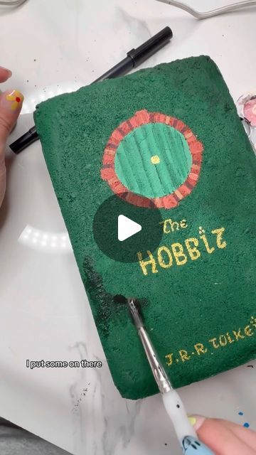 Melani Alberts on Instagram: "What next?? I still have about 4 bricks left. Aka turning this @homedepot brick paver into a book, “the Hobbit”.  Paint supplies: @michaelsstores  #brickpavers #brickpaverbook #thehobbit" Book Cover Painted Bricks, Painting Bricks To Look Like Books, Painted Brick Books, Bricks Painted Like Books, Book Pavers, Book Bricks, Painted Bricks Crafts, Brick Painting, Hobbit Book