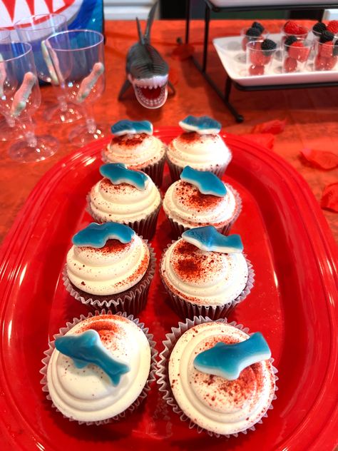 Red Velvet cupcakes with gummy sharks and fancy glasses with sharks for red fruit punch Shark Gummy Cupcakes, Jaws Party Food, Jaws Cupcakes, Gummy Cupcake, First Period Party, Shark Themed Food, Week Snacks, Jaws Party, Gummy Shark