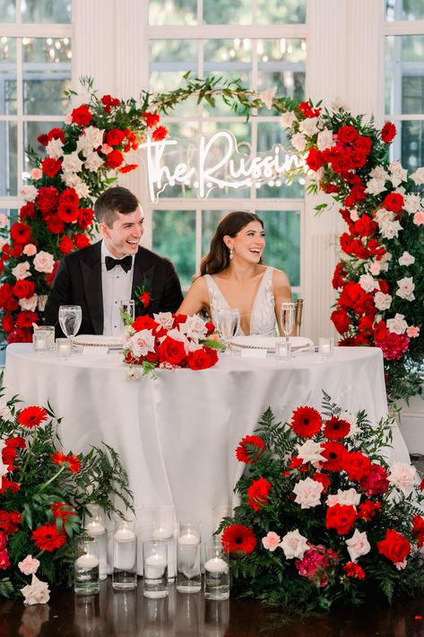 bride and groom sitting at head table with red and pink flowers Romantic Red Rose Wedding Theme, Blush Pink And Red Wedding Theme, Red And White Themed Wedding, Red White Wedding Theme, Blush Pink Red And White Wedding, Bright Red Wedding Theme, Wedding Red And Pink, Red Pink And White Wedding Theme, Red Summer Wedding Color Schemes