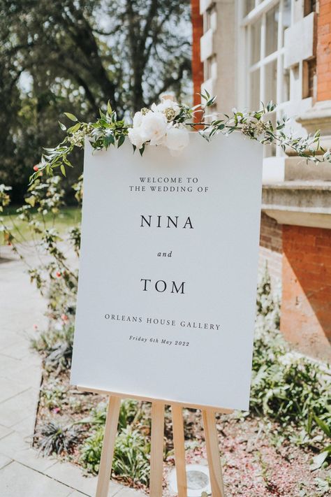 White wedding signage on wooden easel complete with floral decor Floral Easel Welcome Signs, Wooden Easel Wedding, Welcome Sign Easel Flowers, Welcome Wedding Sign Easel, Wedding Sign On Easel, Wedding Boards Signs Entrance, White Wedding Signage, Welcome Signage Wedding, Wedding Sign Easel