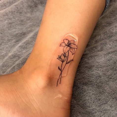 Fine Ankle Tattoo, Lily Flower Tattoos Ankle, Lily Flower Line Tattoo, Lily Flower Tattoos Behind Ear, Fine Line Flower Tattoo Matching, May Lilly Tattoo, Surprise Lily Tattoo, May Lilly Flower Tattoo, Single Lilly Tattoo