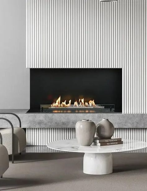 a minimalist nook with an ethanol fireplace and a reeded surround, neutral chairs and a low coffee table with vases is great Planika Ethanol Fireplace, Bio Fireplace Living Rooms, Modern Fireplace Wall With Tv, Modern Fireplace With Tv, Bedroom With Fireplace Master, Fireplace Design Ideas Modern, Tv Wall With Fireplace Modern, Modern Fireplace Wall Living Room, Contemporary Fireplace Ideas