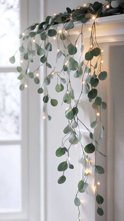 Elegant eucalyptus garland with twinkling lights on a fireplace, framing a white windowsill, creating a warm, soft glow. Christmas Decor With Eucalyptus, Christmas Boho Decor, Decorating With Fairy Lights, Eucalyptus Christmas Garland, Eucalyptus Christmas Decor, Boho Winter Decor, Christmas Greenery Decor, White Winter Decor, Christmas Eucalyptus