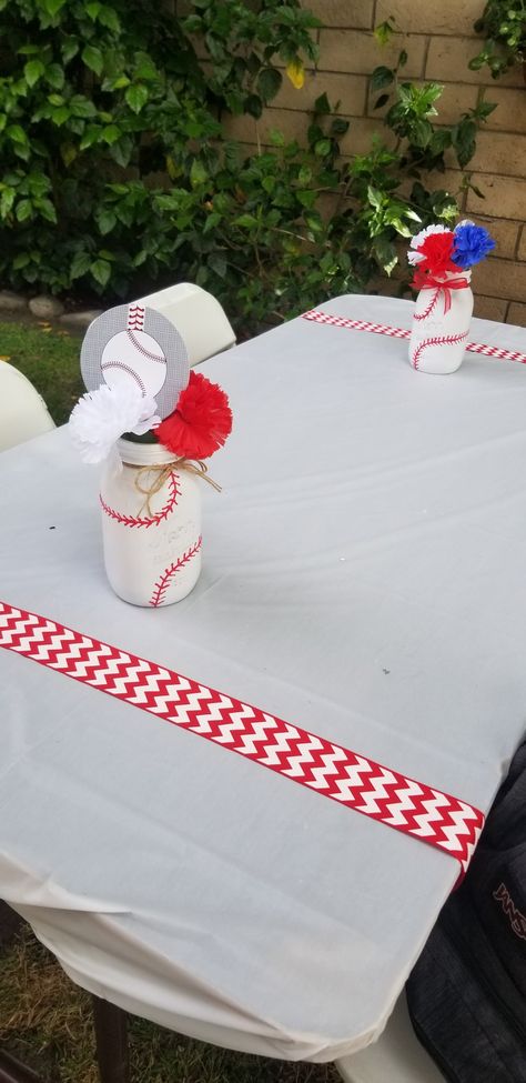 I used Mason jars spray painted white and then used red puffy paint to add the stitches. Tied a red ribbon or twine around the top and added artificial flowers for more pop of color and finished it off with some baseball cutouts glued to popsicle sticks. 2 strips of Red Chevron ribbon added to the white tables to resemble the stitches on baseballs. Great way to accent the baseball themed baby shower. Mason Jar Baseball Centerpieces, Baseball Centerpiece, Baseball Baby Shower Theme, Puffy Paint, Popsicle Sticks, Homemade Crafts, Red Ribbon, Popsicles, White Painting