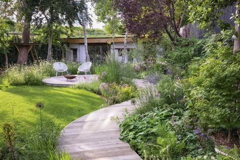 A row of multi-stemmed bay trees creates a pleasing linear effect against the black fence while textural plants, including Persicaria bistorta Alchemilla mollis and Hakonechloa macra, soften the edges of the curving boardwalk from Millboard. Alchemilla Mollis, Small City Garden, Hydrangea Quercifolia, Black Fence, Timber Fencing, Meadow Garden, Cob House, Top Soil, City Garden