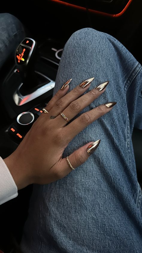 Gold chrome gel-x medium stiletto nails on a black girl’s hand while wearing gold jewelry and rings Chrome Nail Colors, Black Chrome Nails, Gold Chrome Nails, Bronze Nails, Gold Acrylic Nails, Chrome Nails Designs, Metallic Nails, Dark Nails, Prom Nails