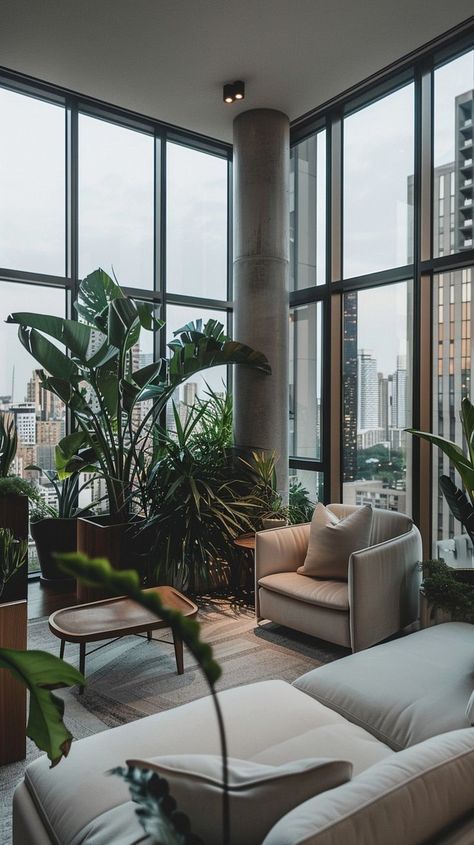 Stylish urban living room with modern design, floor-to-ceiling windows, comfortable seating, and indoor plants. Urban jungle atmosphere. Modern City Apartment, Room With Natural Light, Jungle Vibes, Cozy Seats, Cozy Seating, Urban Oasis, Film Studio, Floor To Ceiling Windows, City Views