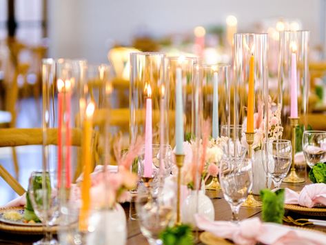 Utilizing colorful pastel taper candles in brass candlesticks and glass hurricanes intermingled with bud vases for long tables as a wedding centerpiece to add color and ambiance to your tablescape. Bud Vases With Taper Candles, Pastel Candles Wedding, Candle Stick Centerpiece, Combermere Abbey, Round Table Centerpieces, Table Scaping, Taper Candles Wedding, Candles For Wedding, Bud Vase Centerpiece