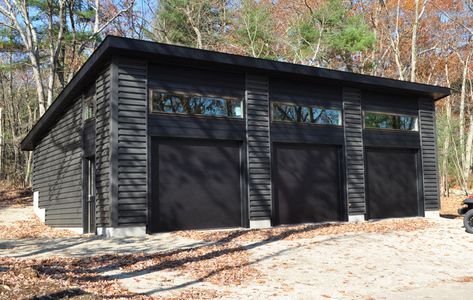 We're loving the sleek lines of this 26x39 Custom Single Slope Garage in Northborough MA. The dark mix of LP lap siding, corrugated metal, dark doors and bronze window frames help make this garage a stunning addition to this beautiful property.   https://neoutdoor.com/garages/  #neoutdoor #newenglandoutdoor #newenglandgarages #customgarages #garagebuilders #northborough #lplapsiding #transomwindows #timberline #garagesboston #garagedesigners Single Slope Garage, Seperate Garage Ideas, Single Slope Metal Building, Mechanic Garage Ideas, Black Metal Garage, Home With Garage, Pole Building Garage, Garage Shop Plans, Metal Garage Buildings