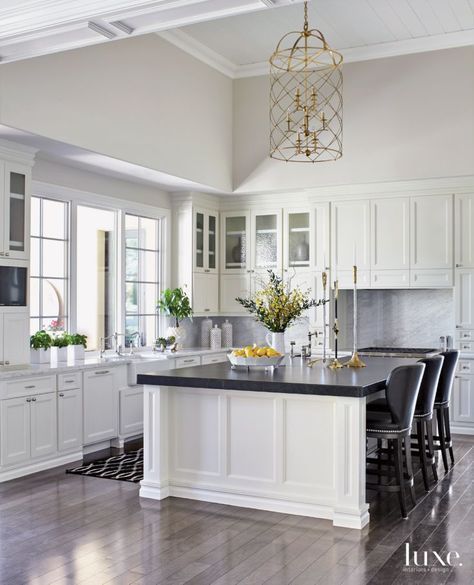 The classic and timeless kitchen includes painted cabinets by R&G Custom Crafting with polished-nickel pulls from Clyde Hardware Co. The perimeter Carrara marble countertops and Cambrian black granite island top are from Arizona Tile; the counter stools are by Swaim. Kitchen With White Cabinets, Black Kitchen Countertops, White Kitchen Traditional, Replacing Kitchen Countertops, Black White Kitchen, Black Island, Kitchen Countertop Materials, Black Countertops, Timeless Kitchen