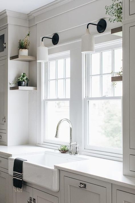 Vintage fluted sconces light a farmhouse sink fitted with a chrome gooseneck faucet mounted to a white quartz countertop over white cabinets. Interior Design Pantry, Kitchen Sconces Over Sink, Lights Over Kitchen Sink, Kitchen Windows Above Sink, Storage Interior Design, Light Above Kitchen Sink, Lighting Above Sink, Before And After Home Interior, Light Over Sink