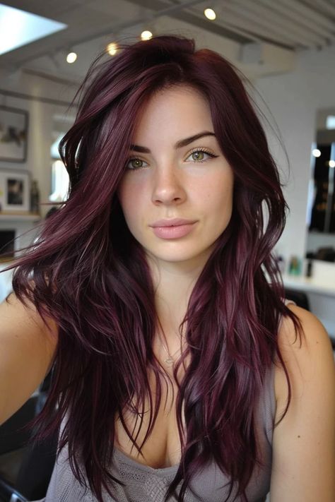 Woman with long, wavy, dark purple hair in a modern, bright room. Black Hair With Magenta Highlights, Cherry Red Hair Pale Skin, Burgundy And Purple Hair, Solid Hair Color Ideas For Brunettes, Dark Violet Hair Burgundy, Sangria Hair Color, Black Hair With Red Tint, Cherry Cola Hair Color Brunettes, Dark Red Violet Hair