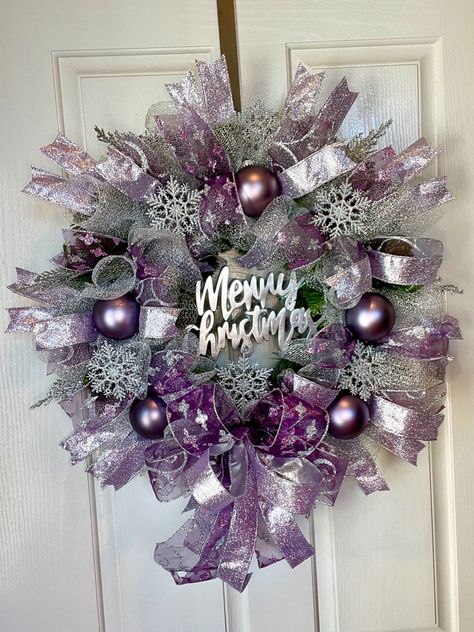 Stunning silver mesh covers this wreath along with three beautiful purple ribbons with glitter accents it also includes 5 purple ornaments and twinkle silver snowflakes. To top it off a silver merry Christmas sign in the middle Purple Mesh Wreaths For Front Door, Purple And Silver Christmas Wreath, Purple Wreaths For Front Door, Purple And Silver Christmas, Purple Christmas Tree Decorations, Purple Christmas Wreath, Plum Christmas, Silver Christmas Wreath, Holiday Centerpieces Christmas